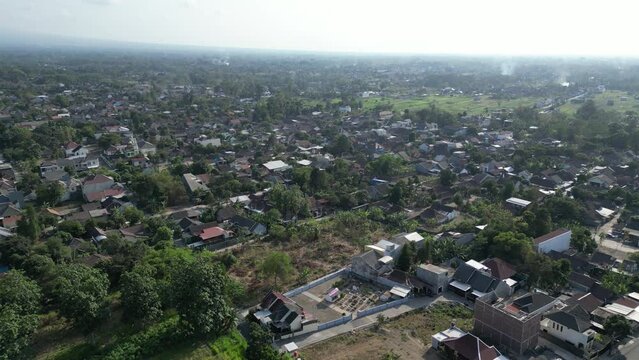 Aerial view of Jogja City with buildings, crowded vehicles traffic in morning sunlight. Sleman cityscape urban landscape. Population density is displacing agricultural land and forests.