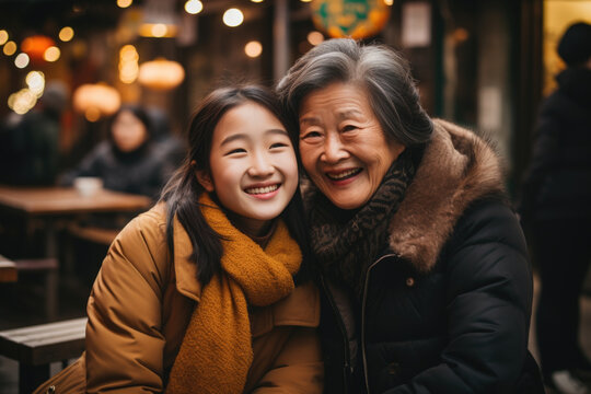 Older woman and young girl posing happily for photograph. This image can be used to depict bond between generations and joy of capturing special moments.