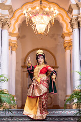 Fototapeta na wymiar Beautiful young woman dressed as Hindu goddess Durga , She is wearing Banarasi Saree and heavy gold Jewellery. Traditional Dancer dressed as Devi Durga.