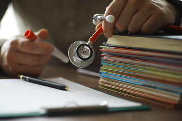 Male doctor search information in book and writtnig prescription, medical stethoscope on the desk...