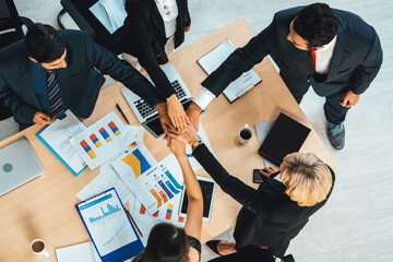 Happy business people celebrate teamwork success together with joy at office table shot from top view . Young businessman and businesswoman workers express cheerful victory show unity support . Jivy