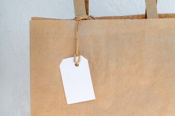 Part of a cardboard bag with handles for delivery or gift, white tag on a rope