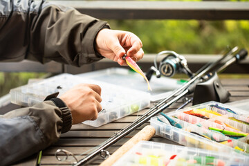 a man threads a fishing hook into a rubber bait, fishing, spinning, preparation for fishing,...
