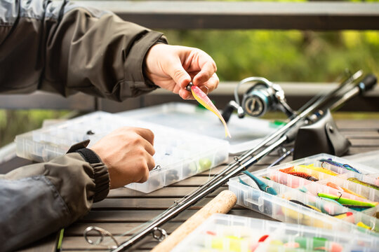 a man threads a fishing hook into a rubber bait, fishing, spinning, preparation for fishing, wobblers, fishing lures