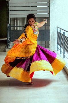 traditional full flare ghaghra choli outfit in gujarati look for folk dance and garba in navratri. woman wearing beautiful hand made oxidized ornaments jewellery and dancing on garba beats. 