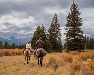 Fotobehang A man and woman horseback riders make their way along a trail in the Ya Ha Tinda Ranch in Alberta, Canada during autumn © Neil