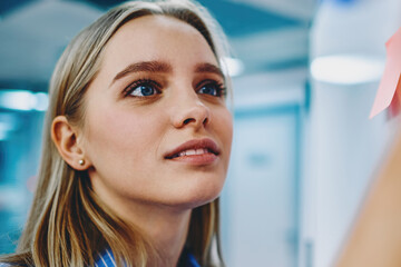 Interested young woman with blonde hair and blue eyes studying in modern classroom - obrazy, fototapety, plakaty