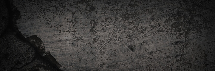 Texture of old cracked concrete wall. Rough dark gray concrete surface with spots, cracks, noise and grain. Dark wide panoramic background for design. Shaded texture with vignette.