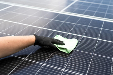 male hand cleaning solar panels with towel to wipe dirty. Solar power for green energy
