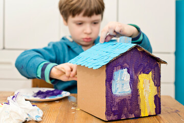 Boy building Little Blue paper House. Activities at home. Creative ideas for preschool or kindergarten teachers. Montessori thematic tool for people with special needs.
