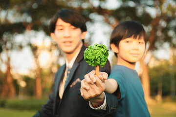 Asian boy and businessman holding paper tree together as Earth day concept as corporate social...