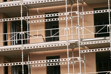 Building an energy efficient condominium house. Scaffolding on a house. Tall building under construction with scaffolds. Investing in the real estate market. Construction Site of New Building.