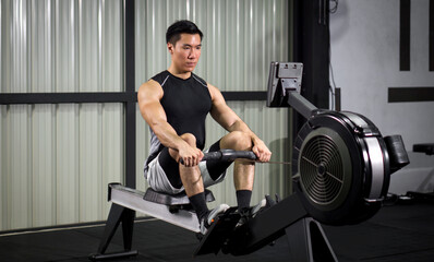 Fitness-conscious man passionately engaging in indoor rowing, in well-equipped gym © chadchai