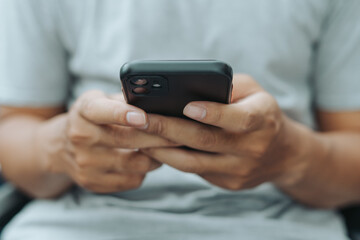Hands of Asian man holding checking touching scrolling smartphone from bed room