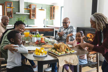 Happy african american multi generation family serving food at thanksgiving dinner