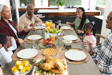 Happy african american multi generation family talking at thanksgiving dinner