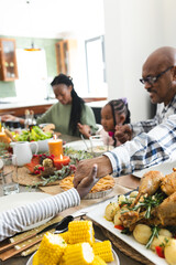 Happy african american multi generation family holding hands at thanksgiving dinner