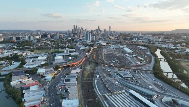 Establishing pull away ascending drone shot of Brisbane City, shot during sunset, flying over the inner city bypass ICB road network. City Skyline standing tall against lovely sunset sky.