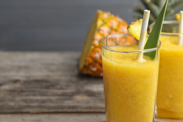 Tasty pineapple smoothie and cut fruit on table, closeup. Space for text
