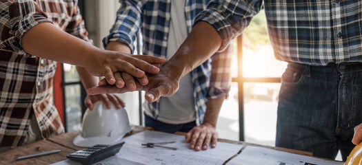 A team of engineers who successfully planned work on a modern home construction project shook hands...