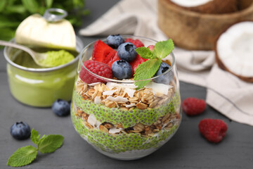 Tasty oatmeal with chia matcha pudding and berries on black wooden table, closeup. Healthy breakfast