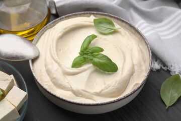 Delicious tofu sauce and basil leaves in bowl on grey table, closeup