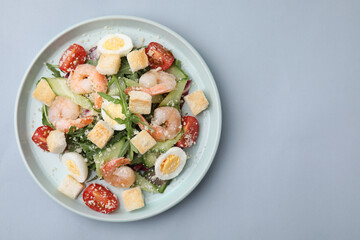 Delicious Caesar salad with shrimps on grey background, top view. Space for text
