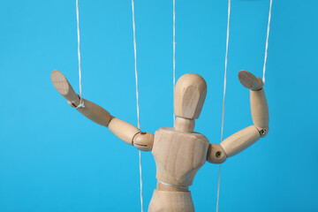 One wooden puppet with strings on light blue background