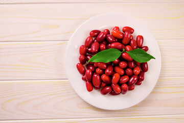 Cornela berries, on a white wooden background. Dogwood berries.