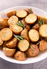 Delicious baked potatoes with rosemary on a gray background