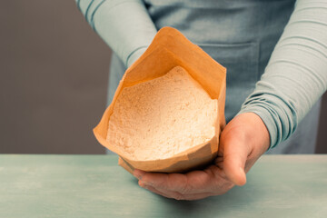 Baker holds paper bag with white wheat flour, baking ingredient for bread, pizza or pastry