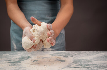 Baker kneading dough for artisan bread or pizza with his hands, prepare ingredients for food,...