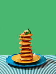 Food pop art photography. Delicious sweet pancakes with maple syrup and batter on plates over green...