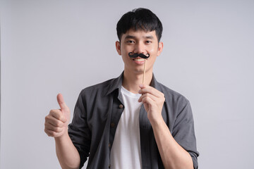 people, party and charity concept - happy young man with fake black moustache party prop