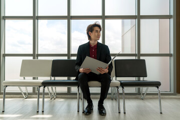 Professional businessman sitting on a sleek chair in a modern office waiting room, exuding confidence and professionalism.