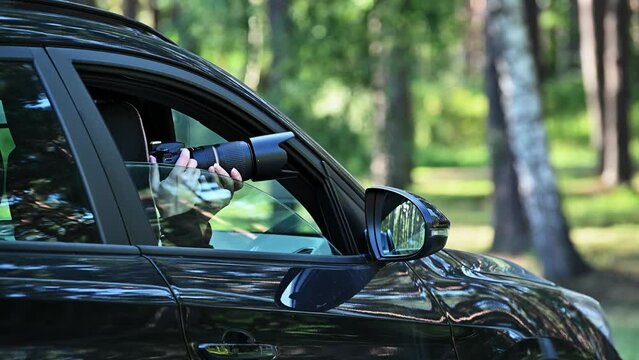 Spy with camera in car. A paparazzi sits in his car and takes pictures of a famous person.