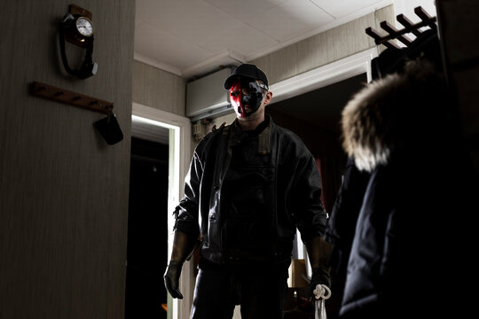 Demon wearing mask standing by doorway in cabin