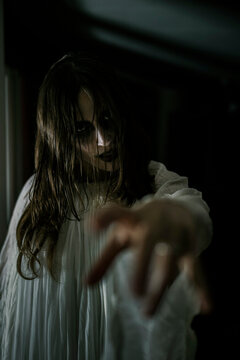 Spooky female ghost reaching out at cabin