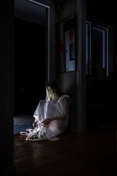 Spooky ghost with rope sitting by doorway in cabin