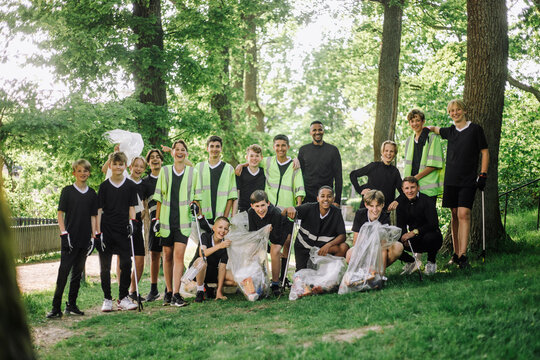 Portrait of happy boys and men with garbage bags - Powered by Adobe