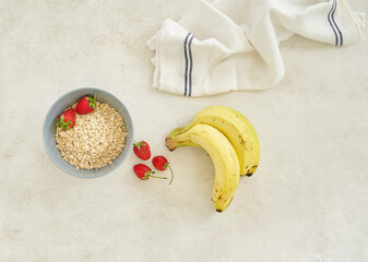 Bananas and granola in the cup, grey background top view.