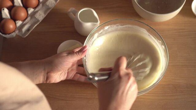 Woman prepares dough for pancakes. Mixing baking ingredients. Cooking, preparing breakfast, dessert