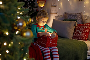 Cute preschool child, blond boy with pet dog, opening presents at home, decorated Christmas room