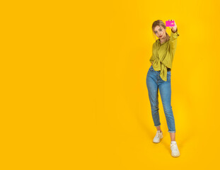 Showing credit card, full body length young blonde caucasian girl showing credit card. Happy woman bank customer client recommend online shopping, e-commerce concept image isolated yellow background.