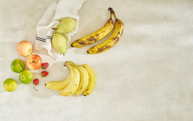 Fruits are on the table grey concrete background, banana apple and napkin, shot from above