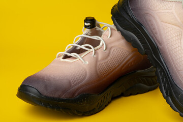 Beige sport running shoes on yellow studio background
