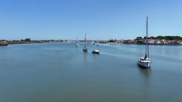 Drone footage flying low over the water among anchored sail yachts in Seixal, south of Lisbon.