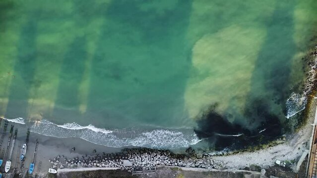 Aerial drone footage of the Shabla lighthouse, beach and surf. Top down high angle shot of green sea and red white vintage lighthouse at the coast of Bulgaria.
