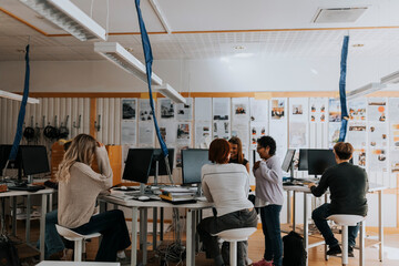Teacher standing amidst students using computers at lab