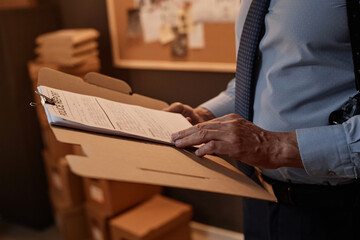 Close up of detective reading police report on clipboard while standing in office, copy space